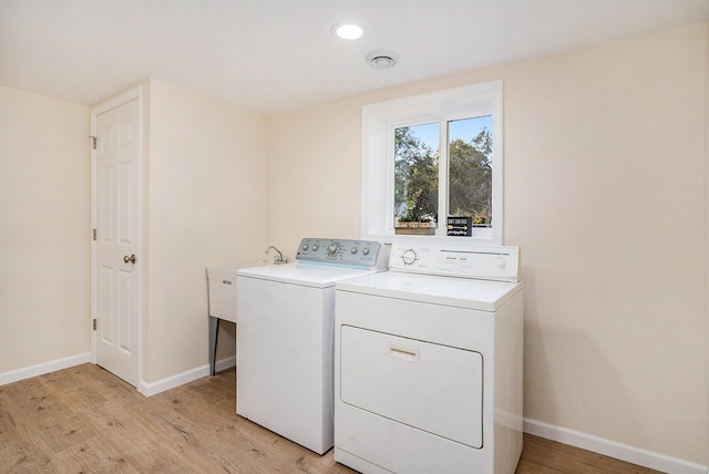 laundry room with washing machine and dryer and light wood-type flooring