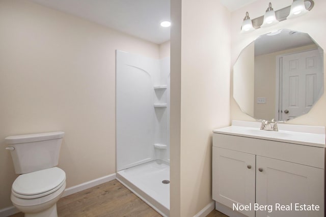 bathroom featuring hardwood / wood-style flooring, toilet, vanity, and walk in shower