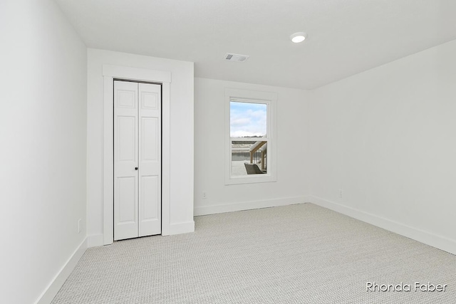 unfurnished bedroom featuring a closet and light colored carpet