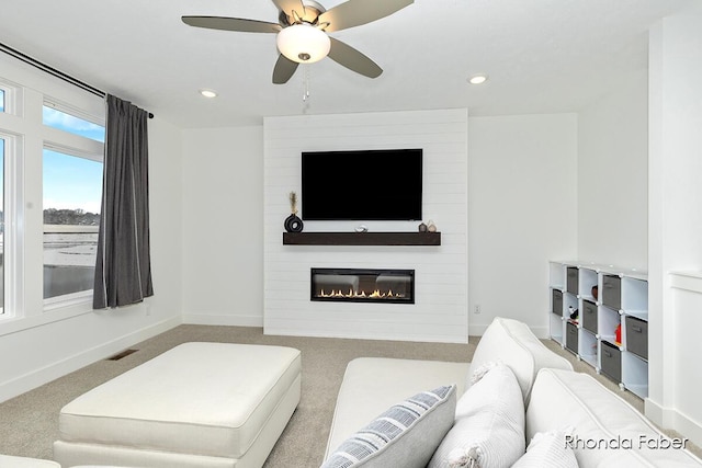 carpeted living room with ceiling fan and a fireplace