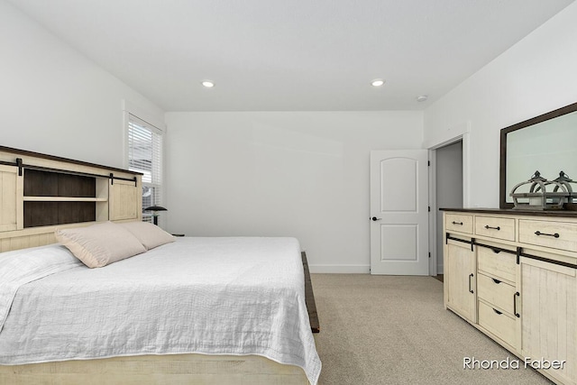 bedroom with a barn door and light colored carpet