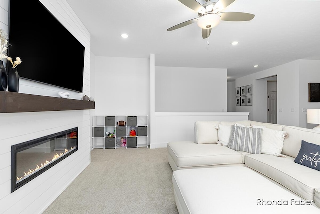 carpeted living room featuring ceiling fan and a fireplace