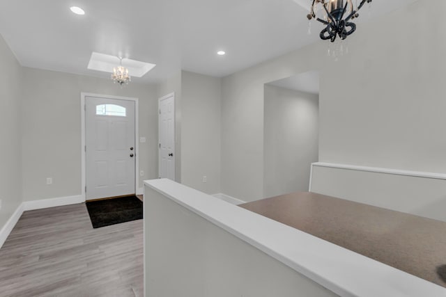 foyer entrance with light hardwood / wood-style flooring and an inviting chandelier