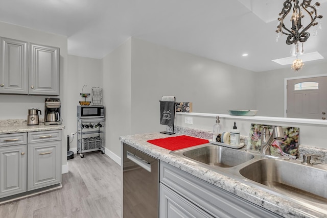 kitchen with appliances with stainless steel finishes, gray cabinetry, sink, pendant lighting, and light hardwood / wood-style floors