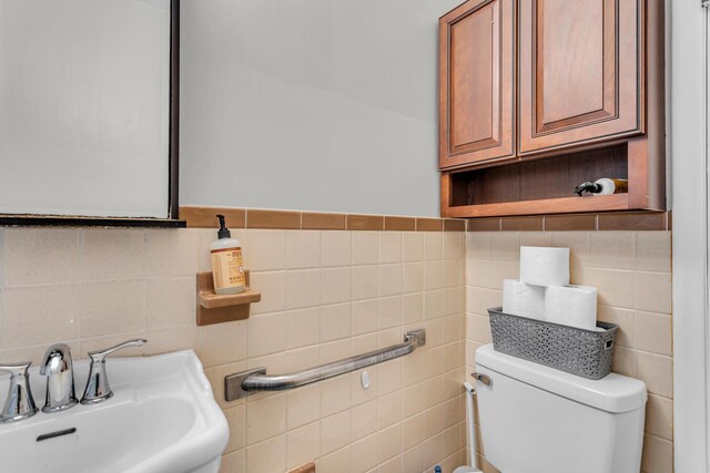 bathroom featuring toilet, sink, and tile walls