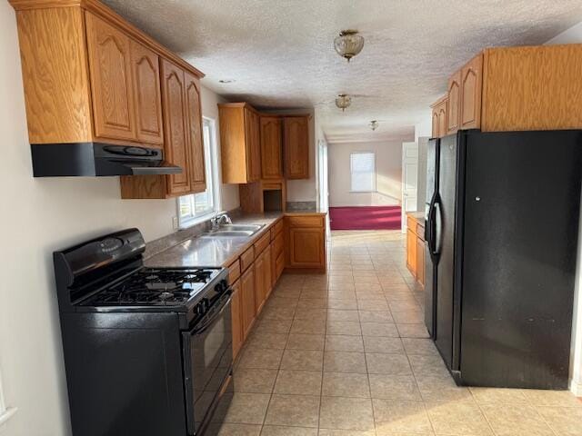 kitchen with sink, light tile patterned flooring, black appliances, and a textured ceiling