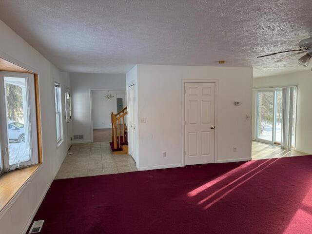 carpeted spare room with ceiling fan and a textured ceiling