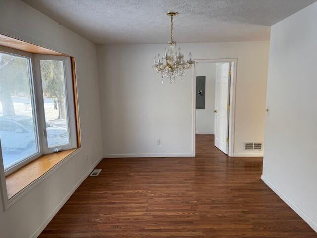 unfurnished dining area featuring dark hardwood / wood-style floors, a textured ceiling, electric panel, and an inviting chandelier