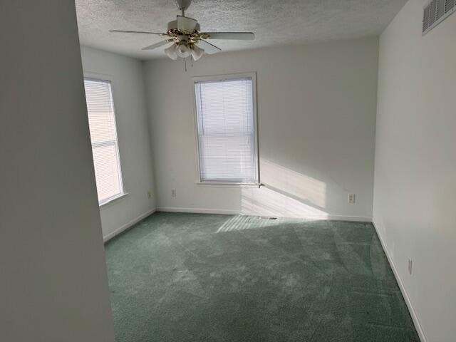 carpeted spare room with ceiling fan and a textured ceiling