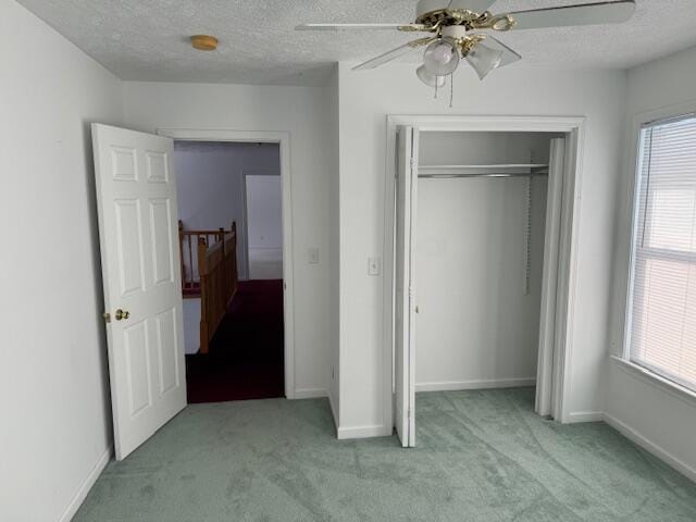 unfurnished bedroom with multiple windows, ceiling fan, light carpet, and a textured ceiling