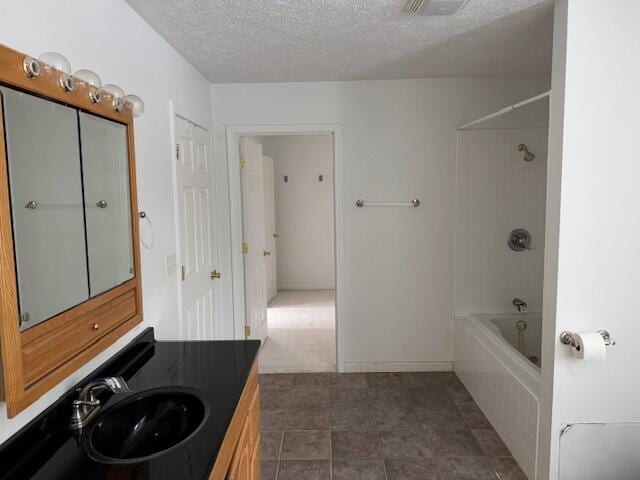 bathroom with tiled shower / bath combo, a textured ceiling, and vanity