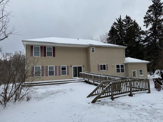 snow covered back of property with a wooden deck