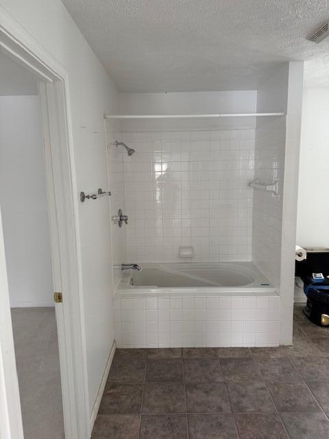 bathroom featuring a textured ceiling, tile patterned floors, and tiled shower / bath combo