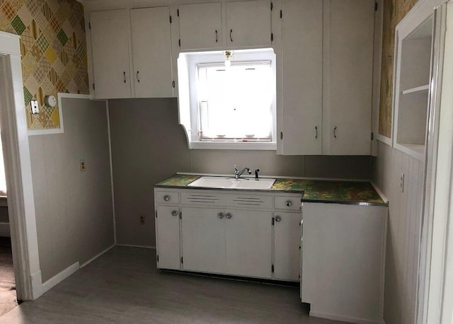 kitchen with sink, white cabinets, and wood-type flooring