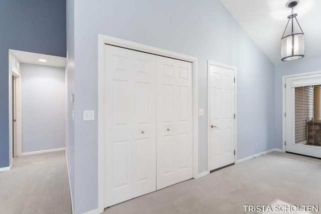 unfurnished bedroom featuring a closet, high vaulted ceiling, and light colored carpet