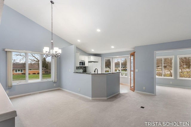 kitchen featuring lofted ceiling, light carpet, white cabinets, hanging light fixtures, and a chandelier