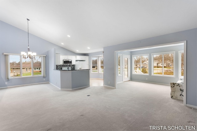 unfurnished living room with lofted ceiling, light carpet, and an inviting chandelier