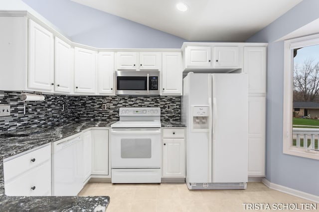 kitchen featuring vaulted ceiling, dark stone countertops, white cabinets, and white appliances