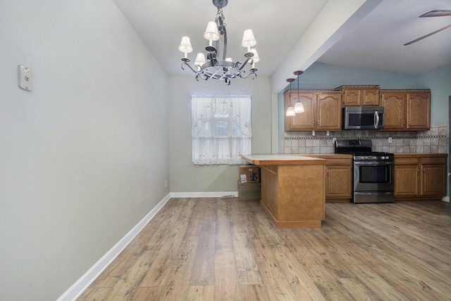 kitchen with ceiling fan with notable chandelier, hanging light fixtures, light hardwood / wood-style flooring, tasteful backsplash, and stainless steel appliances