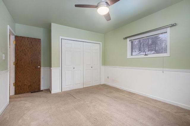 unfurnished bedroom with ceiling fan, a closet, and light carpet