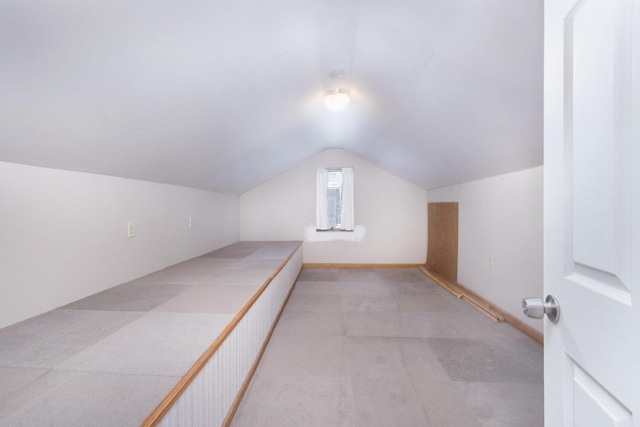 additional living space featuring light colored carpet and vaulted ceiling