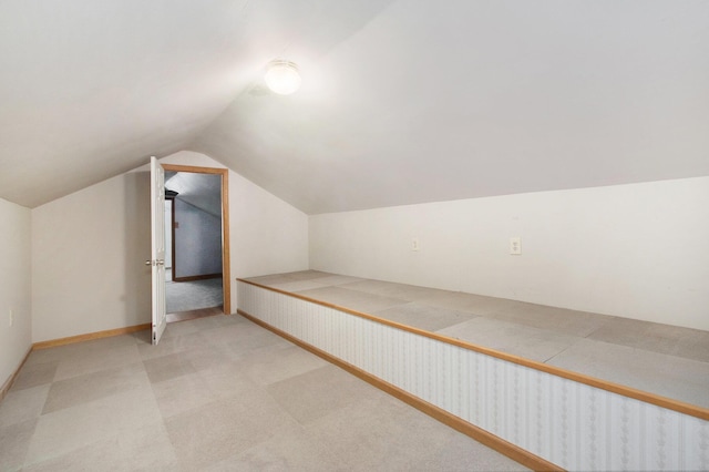 additional living space featuring light colored carpet and lofted ceiling