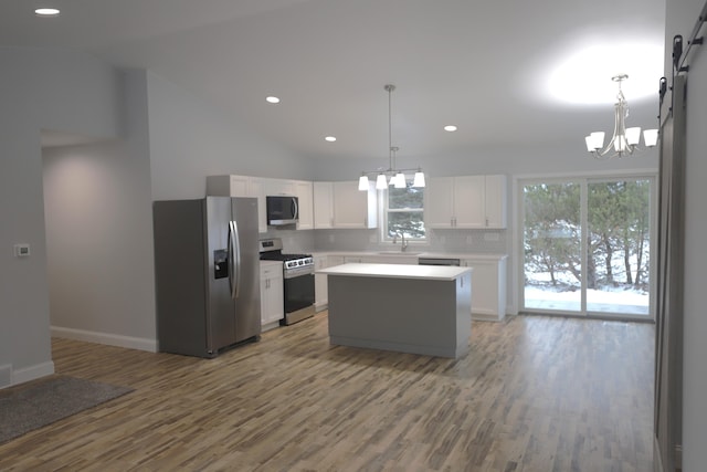 kitchen with appliances with stainless steel finishes, white cabinetry, decorative light fixtures, and sink