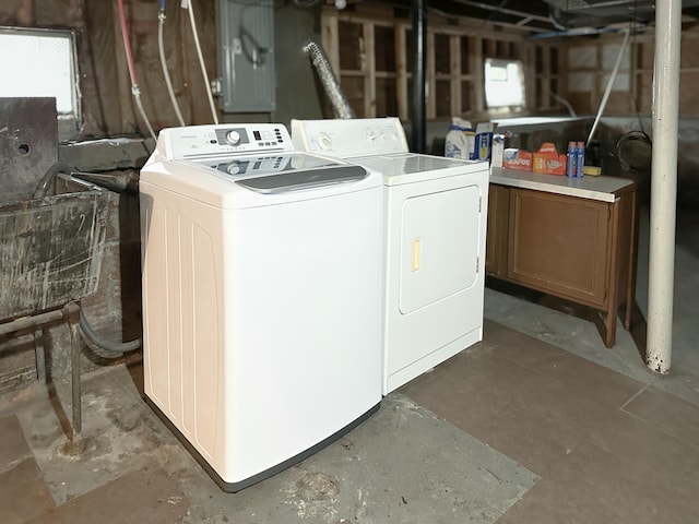 clothes washing area featuring cabinets, a wealth of natural light, and washing machine and clothes dryer