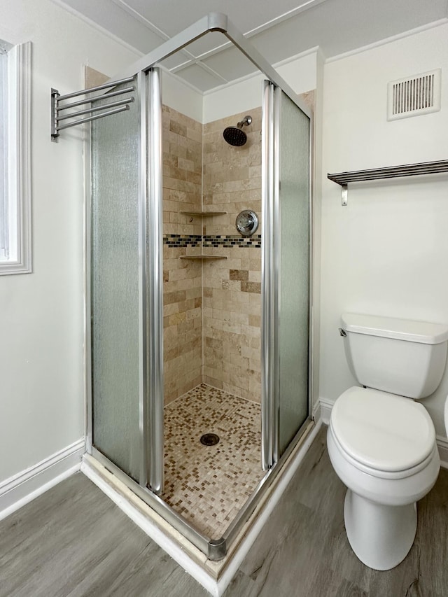 bathroom featuring hardwood / wood-style floors, toilet, and a shower with door