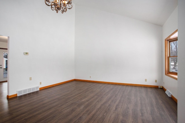 empty room with lofted ceiling, a chandelier, and dark hardwood / wood-style floors