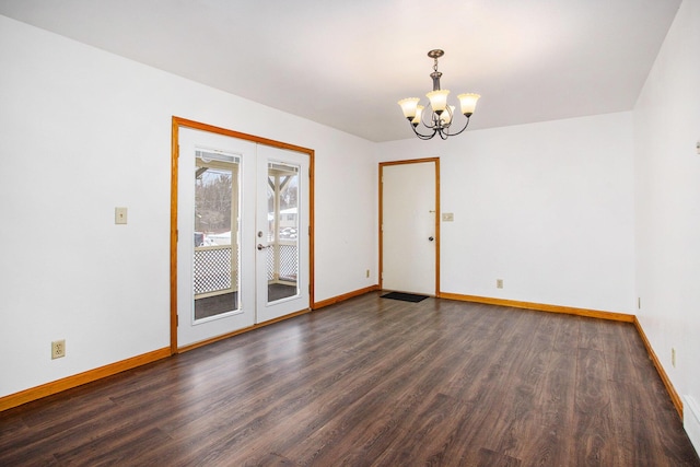 spare room with a chandelier, french doors, and dark hardwood / wood-style flooring