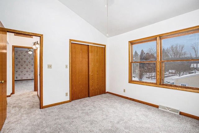 unfurnished bedroom with a closet, light carpet, and vaulted ceiling