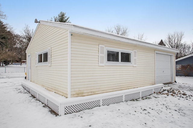 view of snow covered exterior featuring an outbuilding and a garage