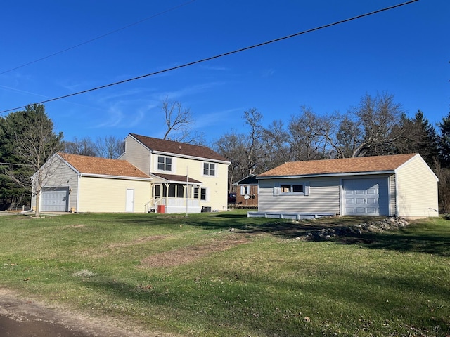 rear view of property featuring a lawn, an outdoor structure, and a garage