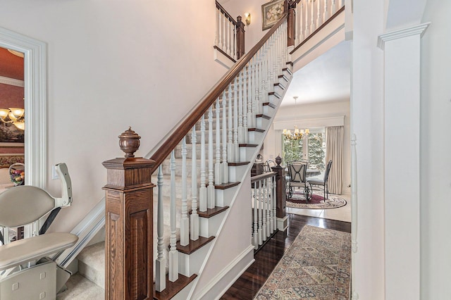 stairway with wood-type flooring and an inviting chandelier