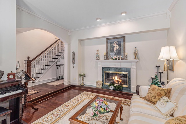 living room featuring a high end fireplace, wood-type flooring, and ornamental molding