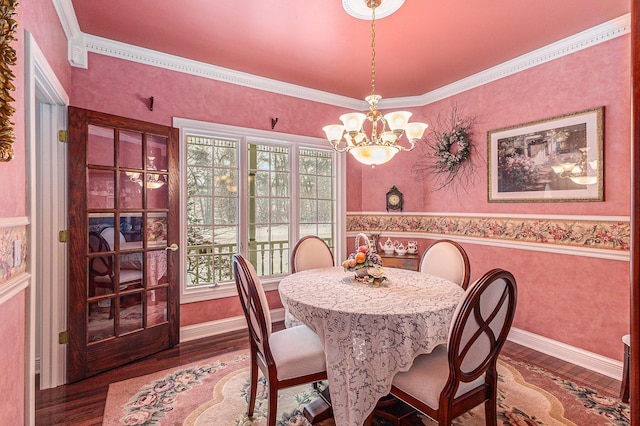 dining space featuring crown molding, wood-type flooring, and an inviting chandelier