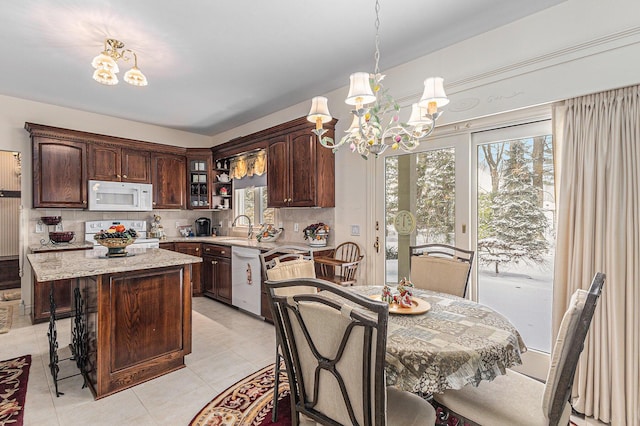 kitchen featuring backsplash, white appliances, a notable chandelier, a center island, and hanging light fixtures