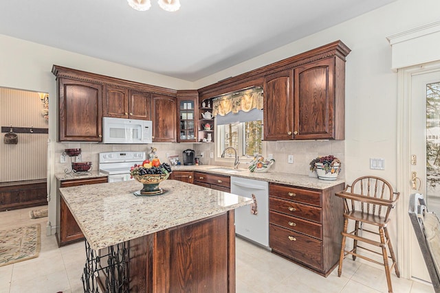 kitchen featuring white appliances, a center island, a wealth of natural light, and sink