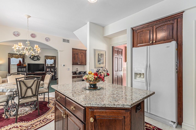 kitchen with pendant lighting, an inviting chandelier, white fridge with ice dispenser, a kitchen island, and light stone counters