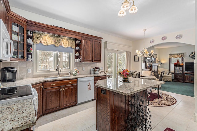 kitchen with decorative backsplash, white appliances, a kitchen island, and sink