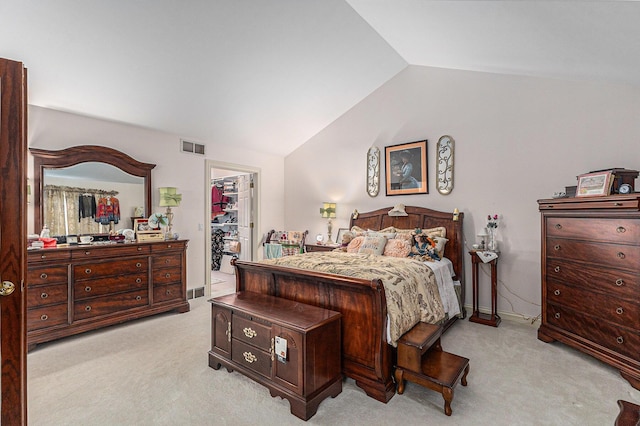 bedroom with a closet, light colored carpet, a walk in closet, and vaulted ceiling