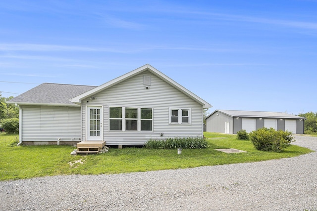 rear view of house with an outdoor structure, a garage, and a yard