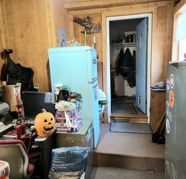 interior space with white refrigerator and wooden walls