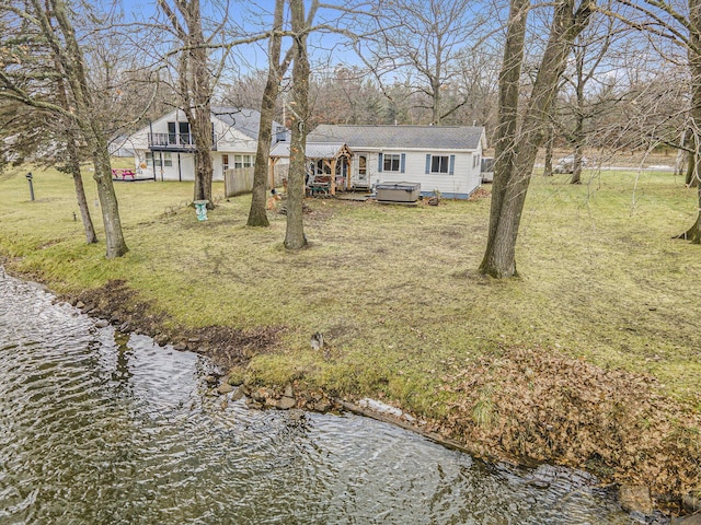 view of front of house featuring a front lawn, a water view, and a hot tub