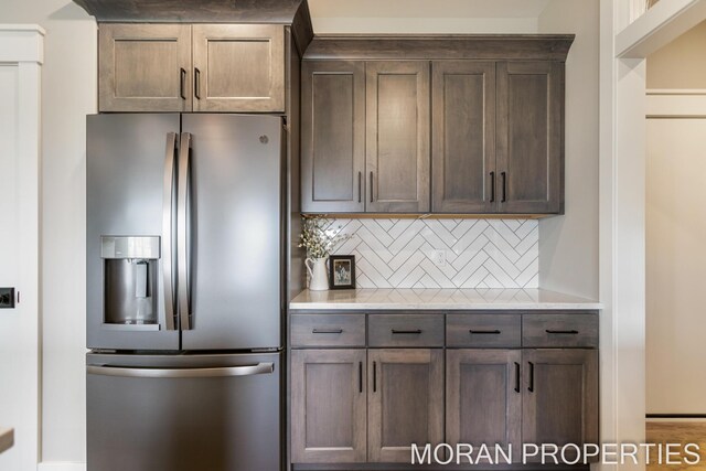 kitchen with backsplash, dark brown cabinetry, and stainless steel fridge with ice dispenser