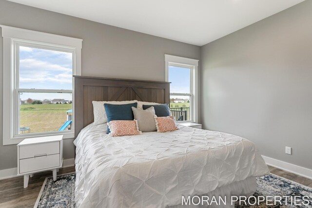 bedroom with multiple windows and dark hardwood / wood-style flooring