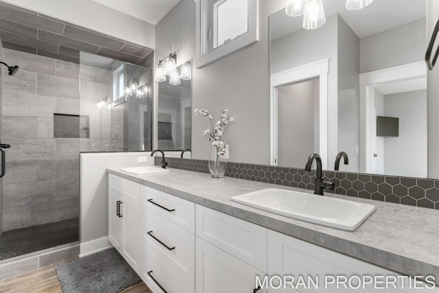 bathroom with tasteful backsplash, hardwood / wood-style floors, vanity, and tiled shower