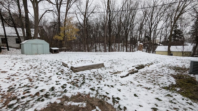 yard layered in snow with a storage shed and central AC