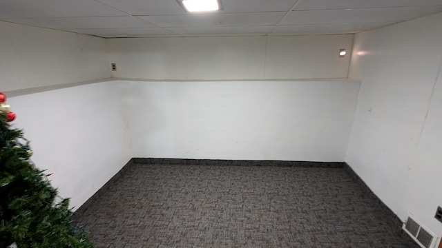 basement featuring dark colored carpet and a drop ceiling